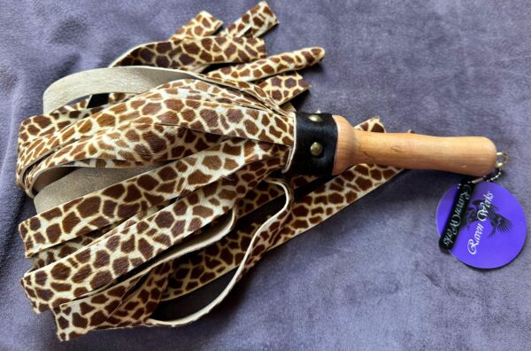 Giraffe print hair on calf hide and cowhide flogger with hand-turned handle.